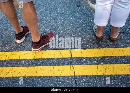 Foto di strada di persone che aspettano in fila mostrando le loro gambe e scarpe. Foto Stock
