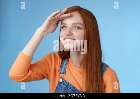 Ragazza guardare lontano distanza girare a sinistra tenere mano fronte di copertura gli occhi caldi luce del sole che sorridevano deliziati a guardare erano palla caduta peer afar gioiosamente squinting ottenere Foto Stock