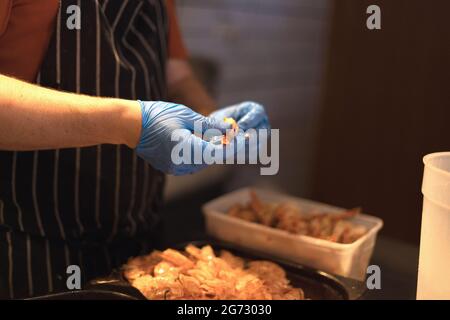 chef peeling gamberi con guanti blu Foto Stock