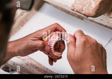 Tecnico dentale che fissa una protesi dentale in un'officina Foto Stock