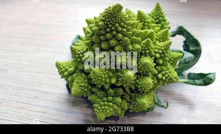 Cavolo Romanesco su sfondo ligneo. Deliziose verdure fresche coltivate in un giardino biologico. Ottimo cibo per vegetariani. Foto Stock