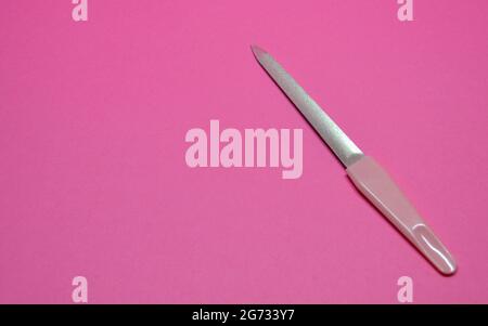 lima per la lucidatura di chiodi per il lavoro del maestro di chiodi su sfondo rosa Foto Stock