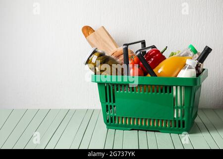 Cestino con cibo sul tavolo vicino alla parete bianca Foto Stock