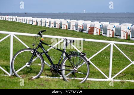 Wilhelmshaven, Germania. 10 luglio 2021. Una bicicletta dell'uomo si appoggia contro una recinzione sulla spiaggia sud in tempo soleggiato di fronte a numerose sedie da spiaggia. Credit: Hauke-Christian Dittrich/dpa/Alamy Live News Foto Stock