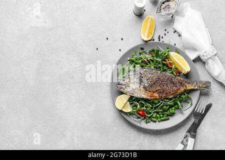 Piatto con dorado fritto e verdure su sfondo chiaro Foto Stock