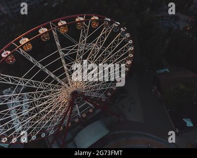 Vista aerea serale sulla ruota panoramica nel centro di Kharkiv, parco divertimenti di Maxim Gorky. Alta attrazione per il tempo libero e l'osservazione della città Foto Stock