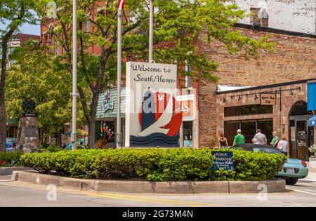 South Haven, MI, USA - 7 giugno 2008: East End della sezione dello shopping di Phoenix Street in centro con verde fogliame e grande cartello di benvenuto in blu e. Foto Stock