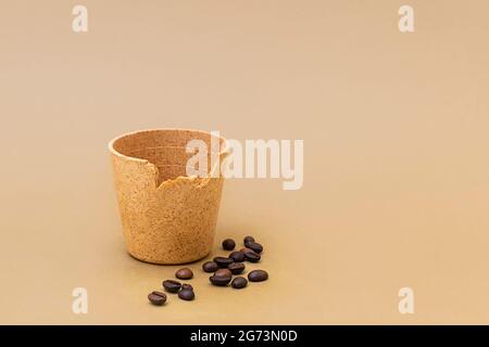 Tazza di caffè o tè con chicchi di caffè arrostiti su sfondo beige. Tazze commestibili come nuova tendenza zero rifiuti Foto Stock