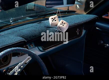 Un paio di dadi decorativi si appendono allo specchio retrovisore di un'automobile d'epoca degli anni '50 in una mostra di auto classica a Santa Fe, New Mexico. Foto Stock