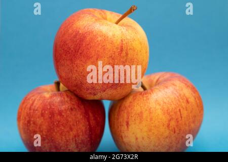 Immagine in primo piano di mele rosse e gialle che formano una piramide su sfondo blu Foto Stock