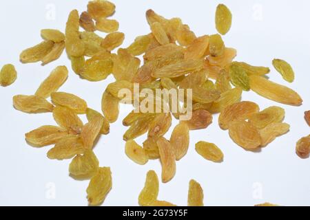 Un primo piano di un mucchio di uva passa dorata su una superficie bianca Foto Stock