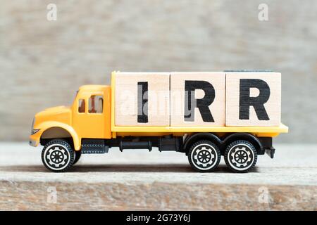 Carrello giocattolo tenere alfabeto blocco di lettere in parola IRR (abbreviazione di tasso interno di ritorno) su sfondo legno Foto Stock