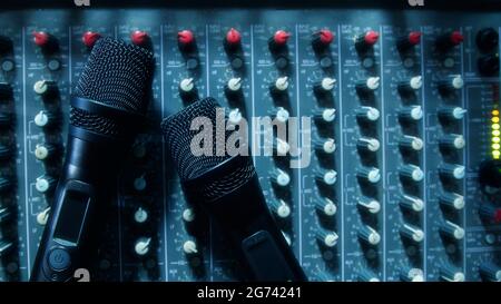 Due microfoni wireless neri con vista dall'alto su un mixer audio professionale in una sala conferenze. Foto Stock