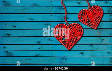 Due cuori su sfondo rustico blu legno. Forma a cuore fatta da filo rosso appendere con corde in legno muro, originale Love Concept Foto Stock