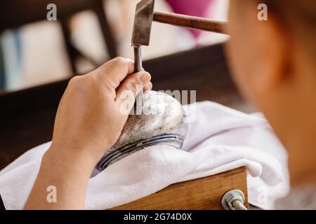 Closeup martello da lavoro artigianale professionale maschile inciso sul capolavoro di arte asiatica artigianale della ciotola in argento. Foto Stock