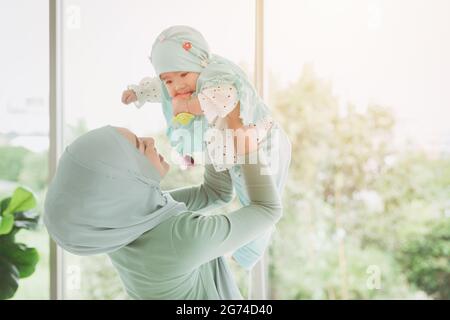 Famiglia musulmana o madre islam con la sua felicità sana bambino giocare insieme in bella casa. Mamma single. Foto Stock