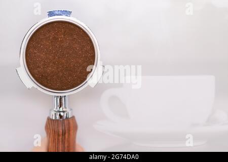 Polvere di caffè macinata in portafiltro con spazio per testo caffè e sfondo tazza di caffè. Foto Stock