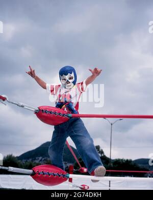 Un ragazzo della folla si insinua nel ring poco prima che i Luchadores (lottatori) inizino la loro prima partita a Ecatepec, Estado de Mexico, giugno 2004 Foto Stock