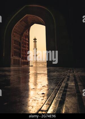 Alba al taj mahal, luce dorata sera. Torre di Minarette incorniciata in un arco Foto Stock
