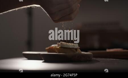 spezie macinate uomo sulla mozzarella su fette di baguette su tavola di legno d'oliva, foto ampia Foto Stock