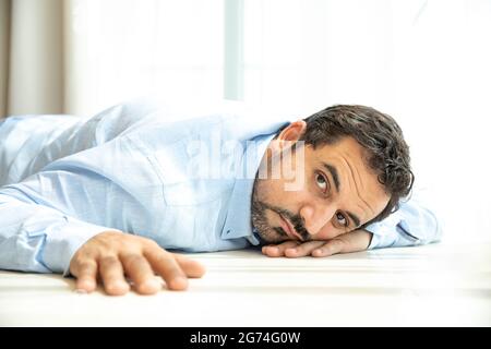 L'uomo arabo di mezza età annoiato che riposa sul pavimento Foto Stock