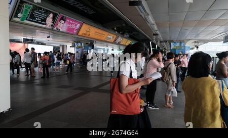 Studente femminile che legge un libro viaggiatori BTS Strap Hangers Computer Riders in attesa di treno al binario binario BTS presso la stazione Siam Square Bangkok Thailandia Foto Stock