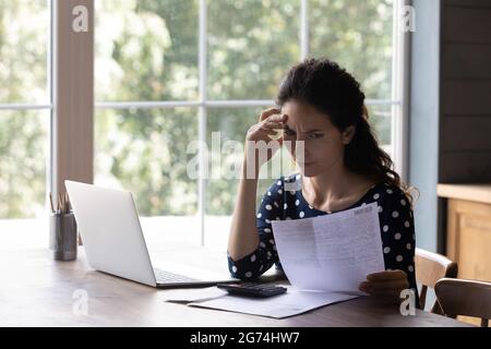 Preoccupazione casalinga che controlla la bolletta di servizio, vedendo erroneamente i costi troppo alti Foto Stock