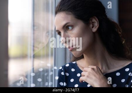 Triste pensava donna ispanica guardando fuori finestra in profondo pensiero Foto Stock