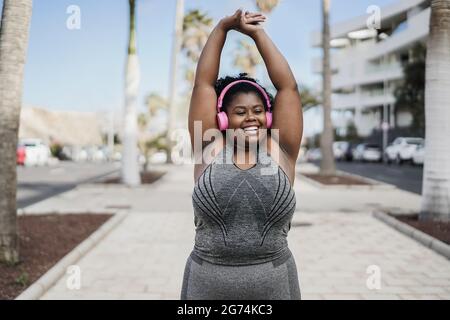 Felice donna africana curvy che fa la routine di allenamento all'aperto nel parco cittadino - Focus on Face Foto Stock