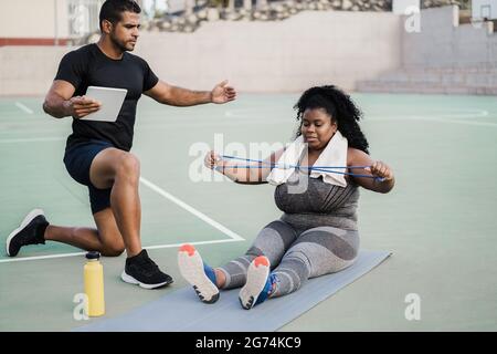 Donna curvy e personal trainer facendo pilates sessione di allenamento all'aperto - fuoco principale sulla faccia della ragazza Foto Stock