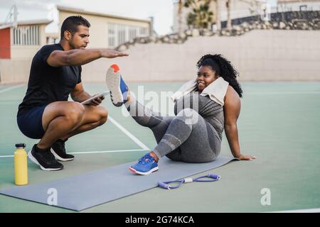 Donna curvy e personal trainer facendo pilates sessione di allenamento all'aperto - fuoco principale sulla faccia della ragazza Foto Stock