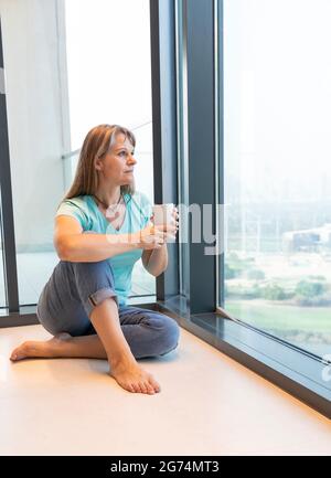 donna di mezza età che riposa a casa, bevendo caffè Foto Stock