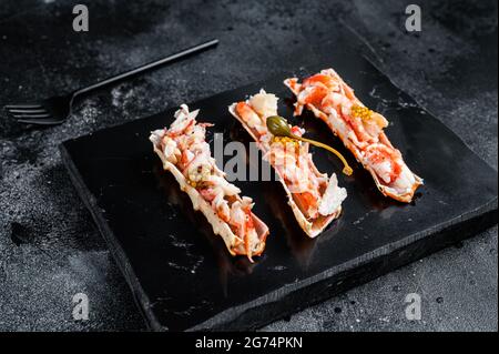 Granchio di carne di gamba in una pecorella con le erbe. Sfondo nero. Vista dall'alto Foto Stock