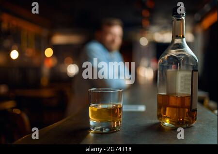 Bottiglia di alcol e bicchiere al bancone al bar Foto Stock