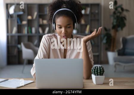 Primo piano donna afroamericana in cuffie che chiacchierano, utilizzando un computer portatile Foto Stock