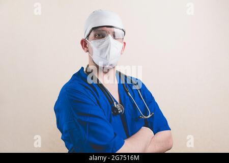Giovane medico ritratto in tuta blu con stetoscopio e con le mani sul petto isolato su fondo liscio Foto Stock