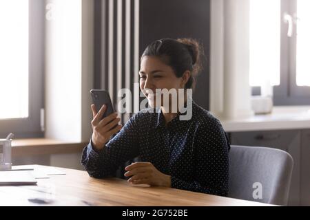 Felice entusiasta donna indiana che usa lo smartphone per videochiamare Foto Stock