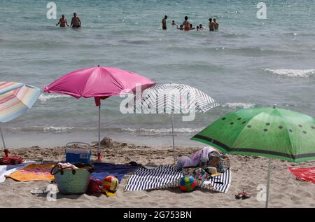 Maorca, Spagna. 11 Luglio 2021. La gente bagnano nel mare alla spiaggia Playa de Muro nel nord di Maiorca. Il governo federale ha dichiarato tutta la Spagna con Maiorca e le isole Canarie in vista del rapido aumento del numero di Corona nell'area a rischio. Gli effetti pratici per i vacanzieri di Maiorca sono limitati per il momento. Credit: Clara Margais/dpa/Alamy Live News Foto Stock