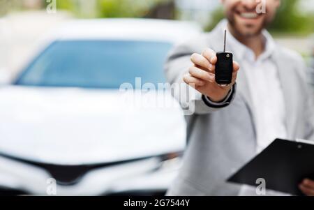 Auto business, vendita auto, affare, gesto e concetto di persone. Il concessionario dà la chiave al nuovo proprietario Foto Stock