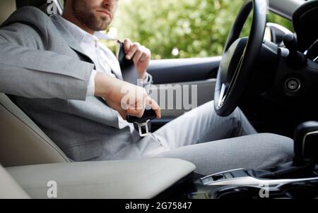 Sii sicuro e giovane seduto sul sedile di guida dell'auto, allacciando la cintura di sicurezza e pronto all'uso Foto Stock