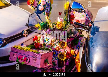 Uno scooter che si dipinge in fiori violacei per strada Foto Stock