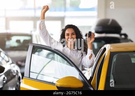 Donna emozionale bruna acquisto auto nuova, showroom interno Foto Stock