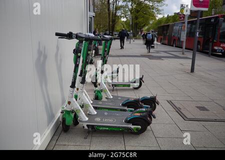 KIEL, GERMANIA - 18 maggio 2021: Kiel, Germania, 18 2021 maggio, nuova mobilità urbana, scooters elettrici in affitto, e-scooter, calce azienda, in background un autobus Foto Stock