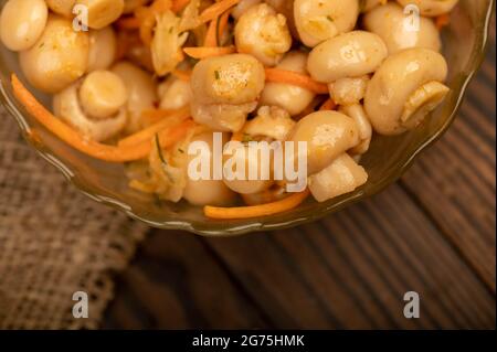 Funghi salati in un piatto di vetro su un tavolo di legno. Primo piano fuoco selettivo Foto Stock