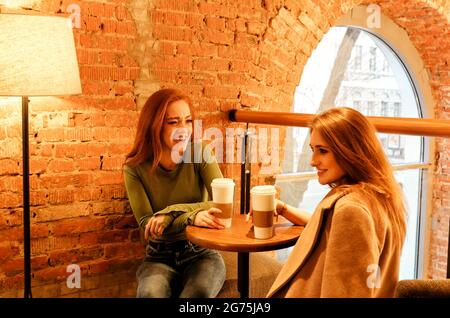 Felici le giovani amiche multirazziali che siedono al tavolo con bevande fredde al bar durante l'orario di pranzo Foto Stock