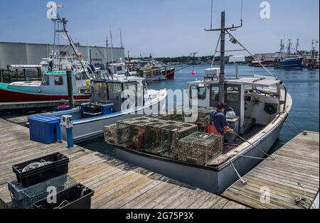 Lobster Boat docking: Una piccola barca da pesca carica di trappole di aragosta si attacca a un molo commerciale di pesca in Massachusetts. Foto Stock