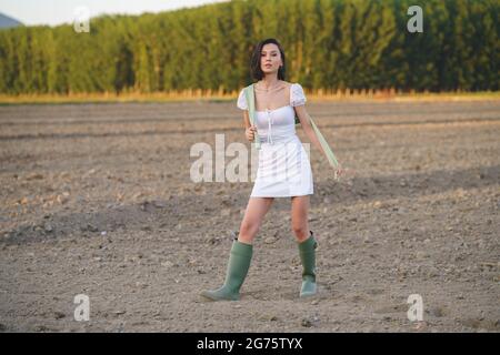 Donna asiatica, camminando in campagna, indossando un vestito bianco e verdi gialle. Foto Stock