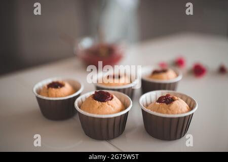 Gustosi cupcake con ripieno di marmellata di fragole soggiorno sul tavolo da cucina primo piano. Preparazione per feste di compleanno o matrimoni. Ora della colazione. Foto Stock