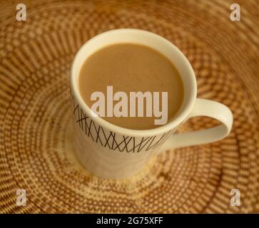 Caffè con latte e cannella in tazza su una tovaglia di tessuto marrone Foto Stock