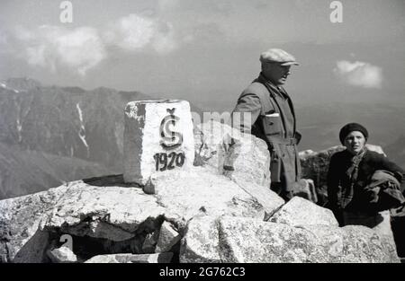 1935, storico, un uomo e una signora escursionista in piedi su una cima rocciosa, accanto a una pietra quadrata, che è stata scolpita con la lettera S e l'anno del 1920. Essi sono in quella che allora era conosciuta come Cecoslovacchia, in piedi nei Sudeti, parte di serie di catene montuose in Europa centrale e da cui i tedeschi Sudeti e il Sudetenland sono chiamati in seguito. Foto Stock